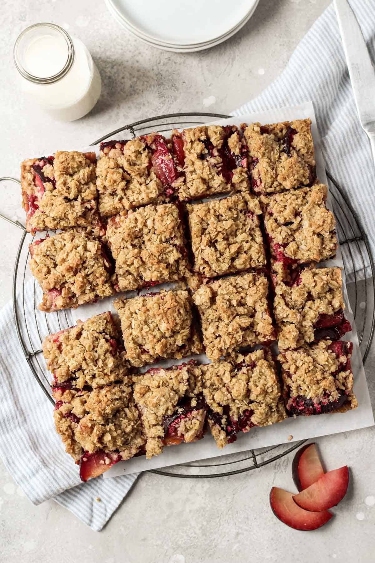Easy plum bars cut into squares on a round french wire cooling rack.
