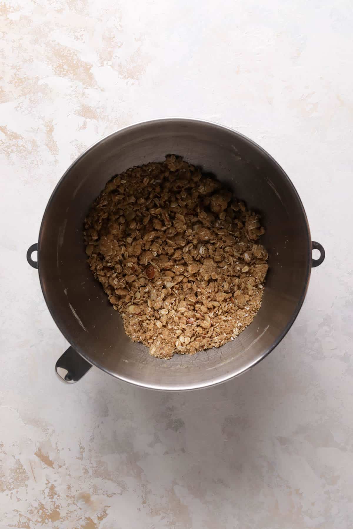 Crumble topping dry ingredients mixed with butter in a stand mixer bowl into a crumble consistency.