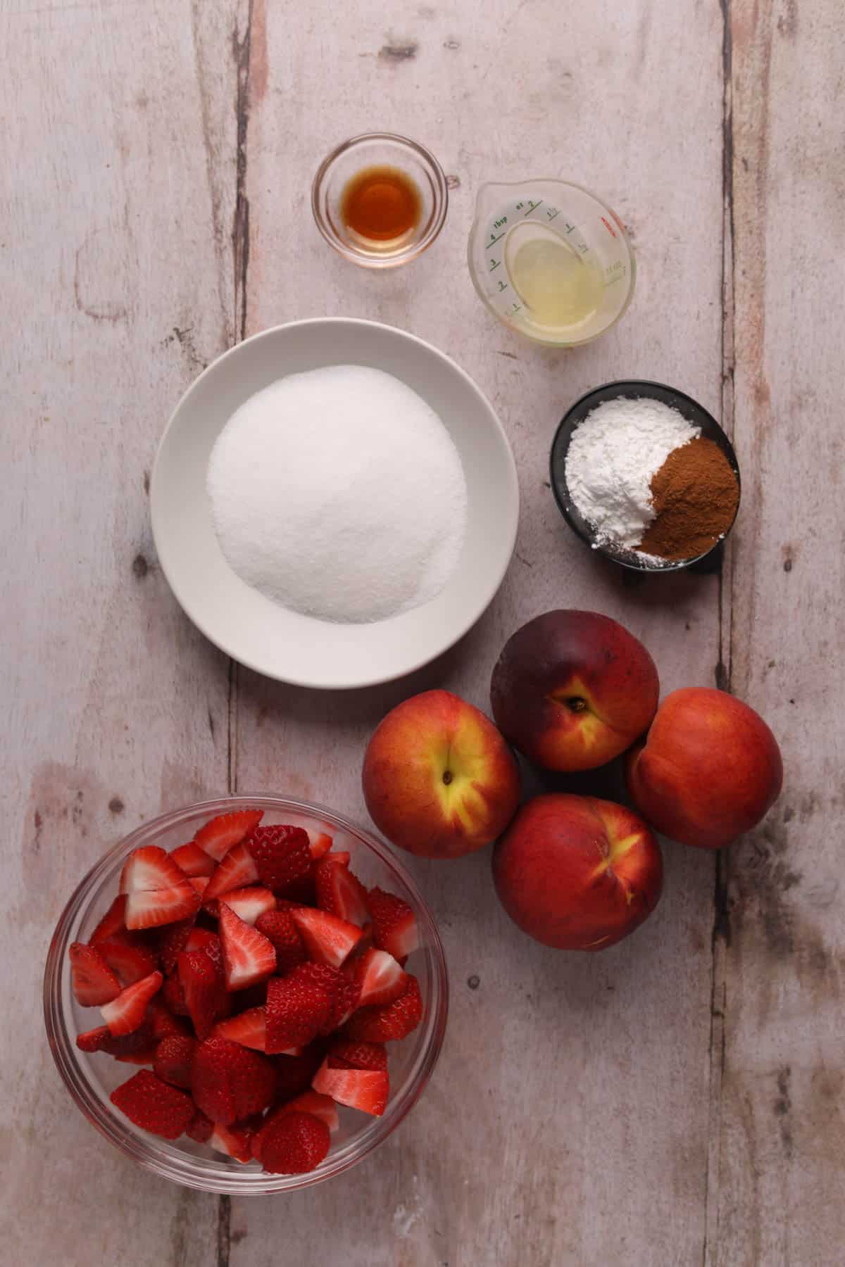 Ingredients for strawberry peach crisp filling in bowls.