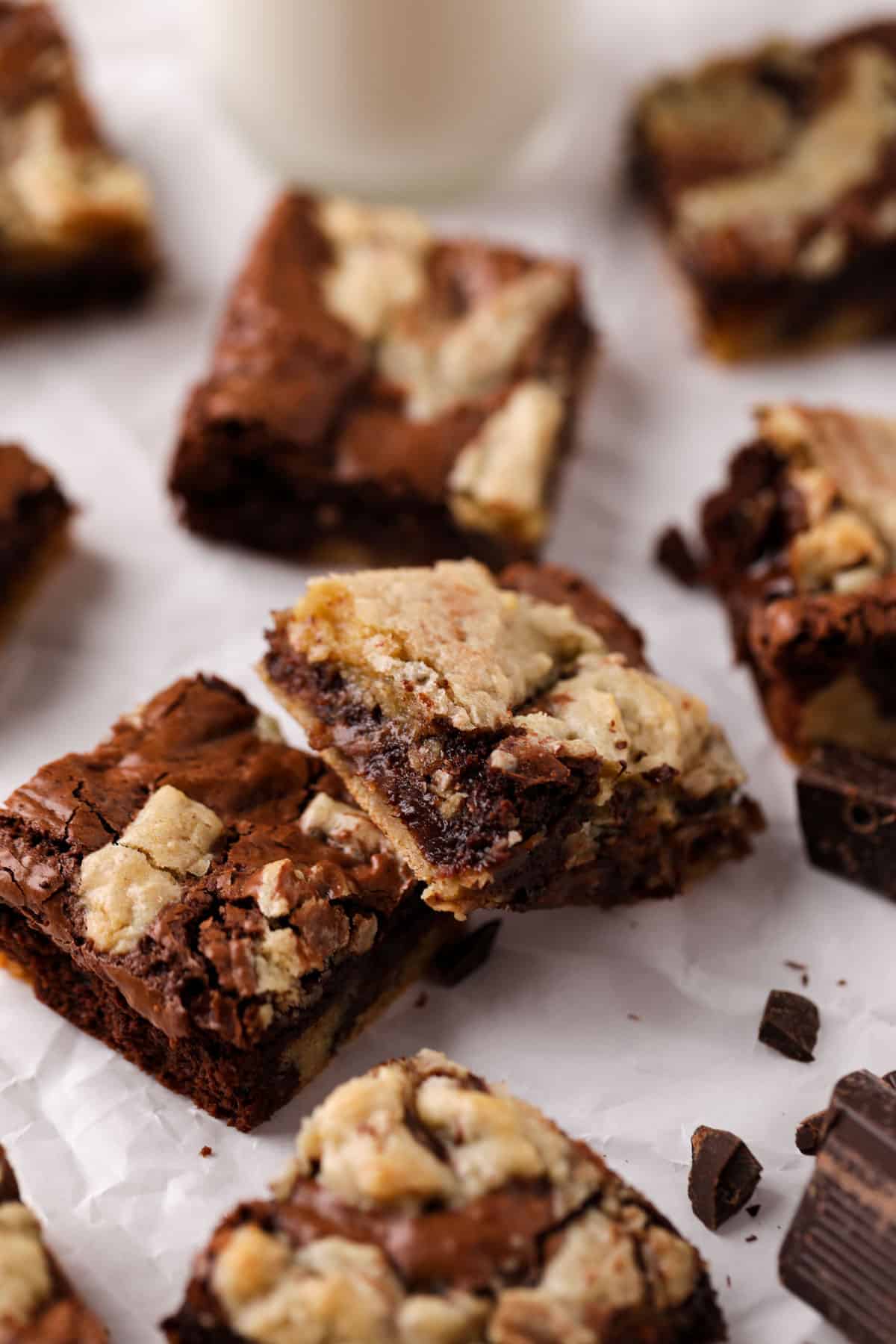 Brownie blondies cut in square are randomly arranged on parchment paper.