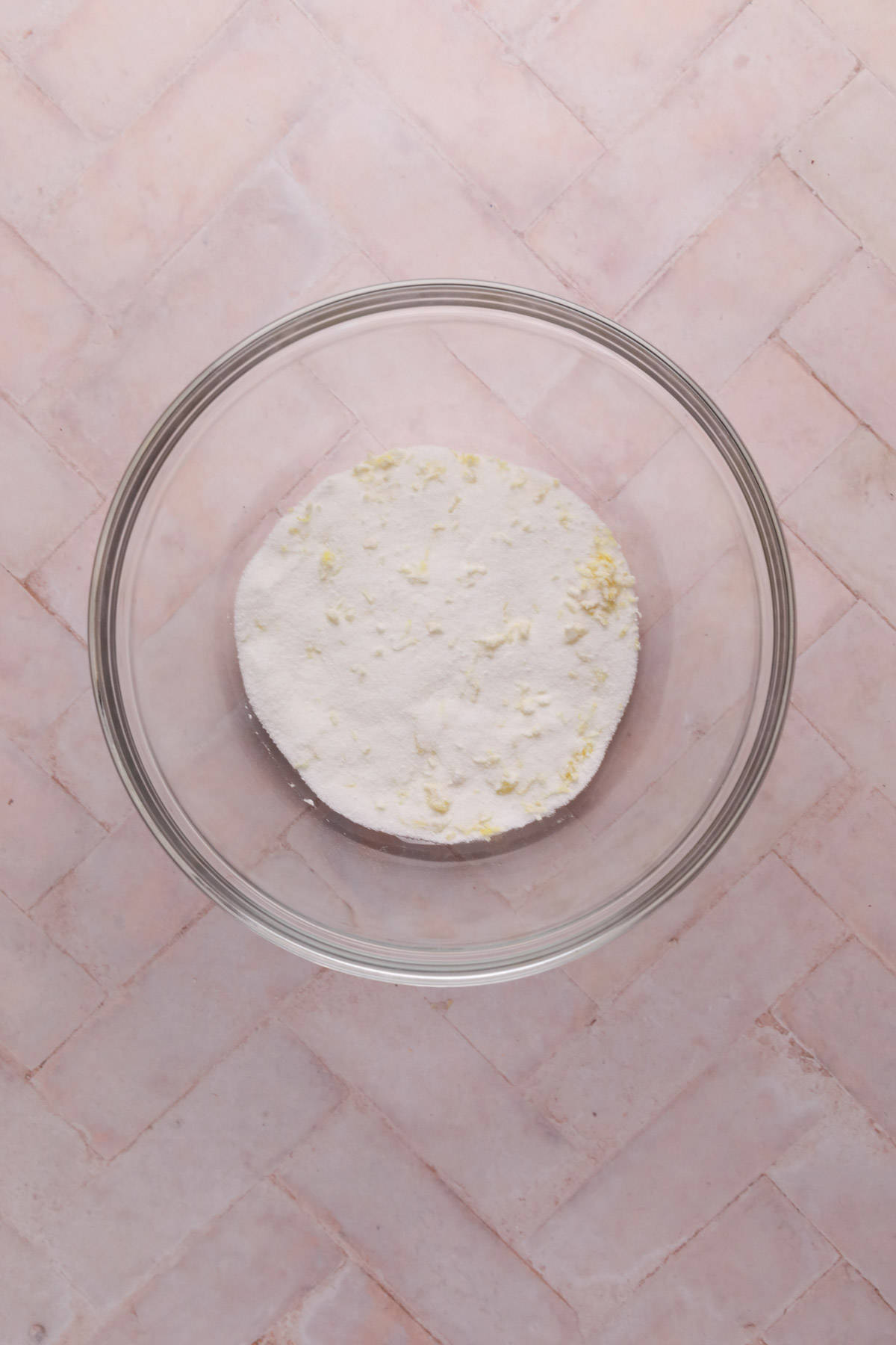 Sugar and lemon zest combined in a glass bowl.