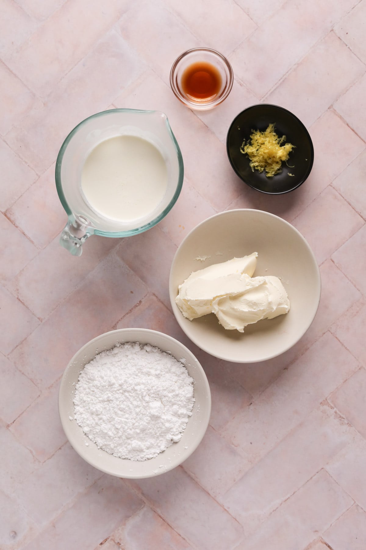 Mascarpone frosting ingredients in bowls on a flat tiled surface.