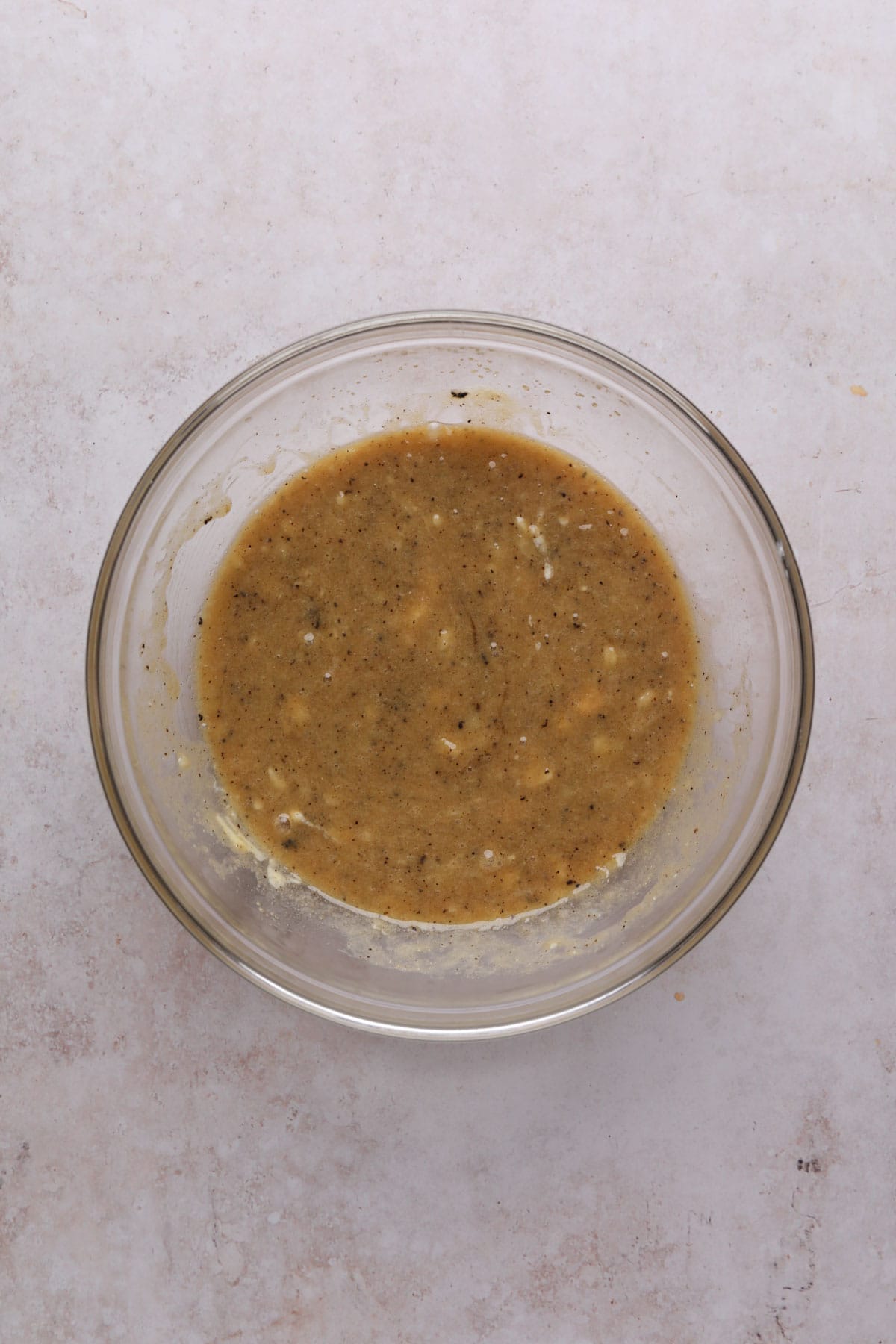 Wet ingredients and brown sugar mixed in a glass bowl for banana cookies.