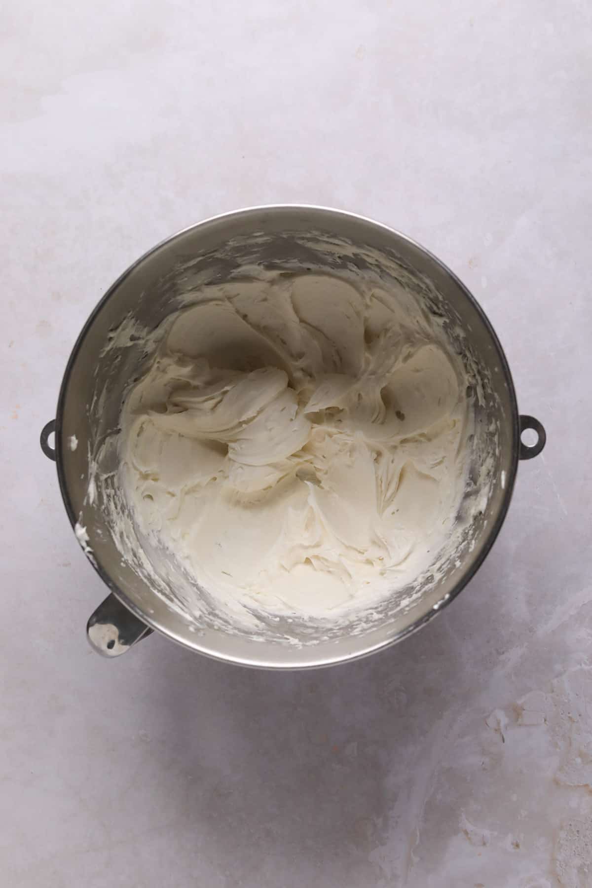 Cream cheese frosting mixed in a stand mixer bowl.