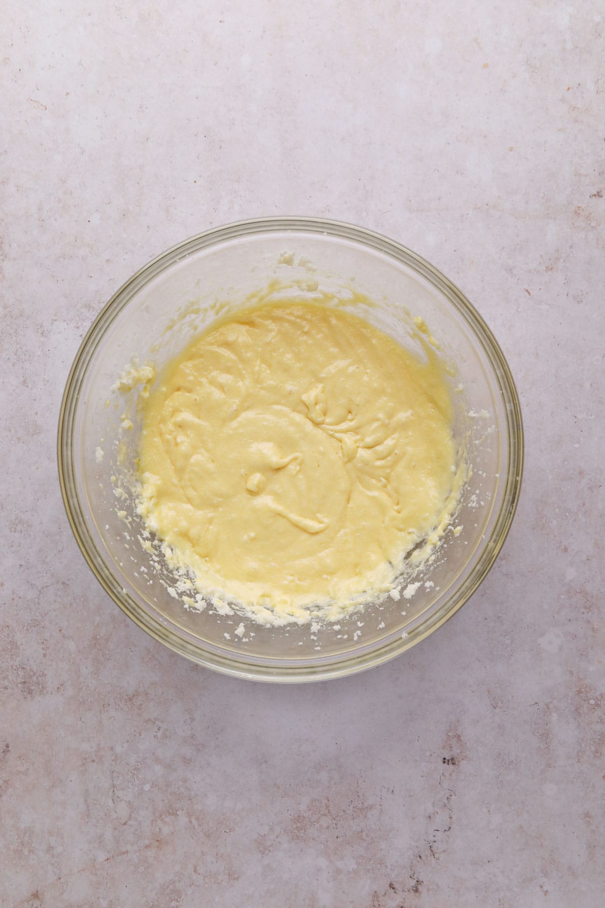 Overhead shot of creamed butter and sugar mixed with egg whites and vanilla in a glass mixing bowl for funfetti cake.