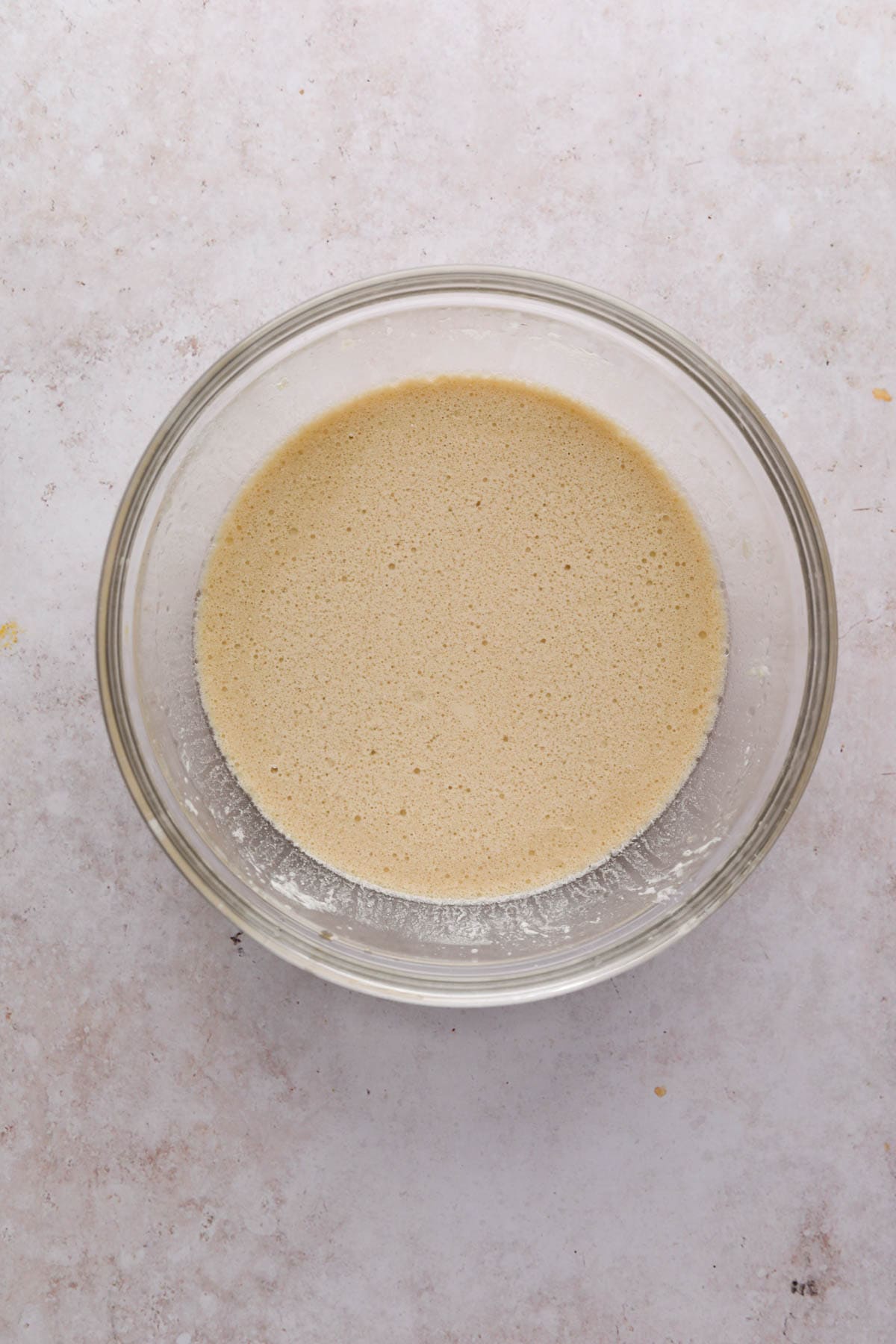 Whisked wet ingredients for chocolate cake in a glass mixing bowl.