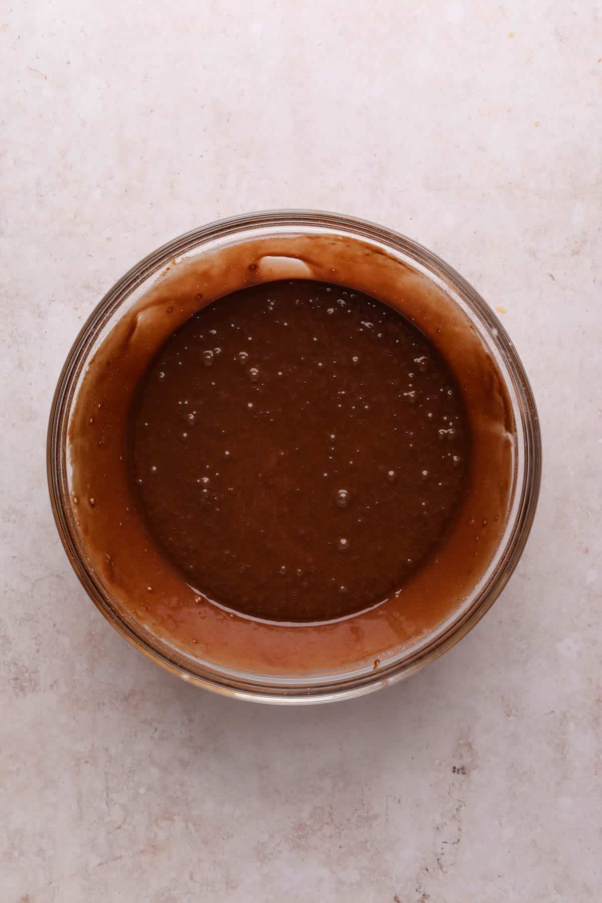 Wet and dry ingredients for chocolate cake combined in a glass mixing bowl.