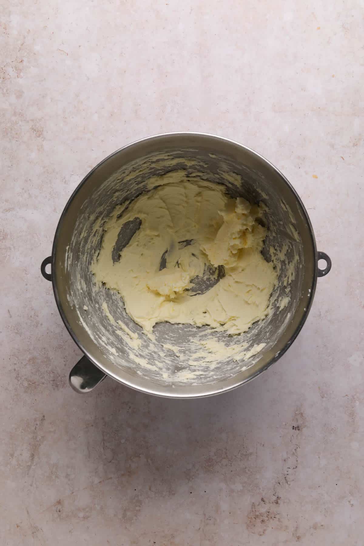 Beaten butter in a metal stand mixer bowl.