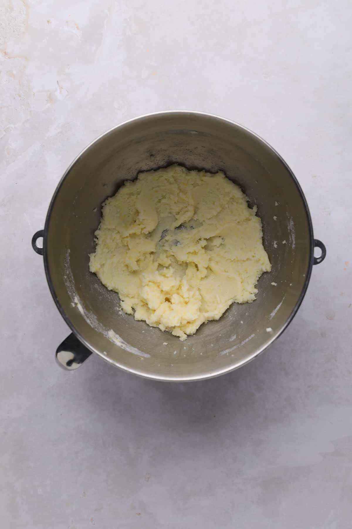 Creamed butter and sugar for lemon cupcakes in a metal stand mixer bowl.