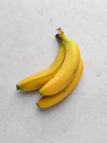 Bunch of three bananas on a flat surface.
