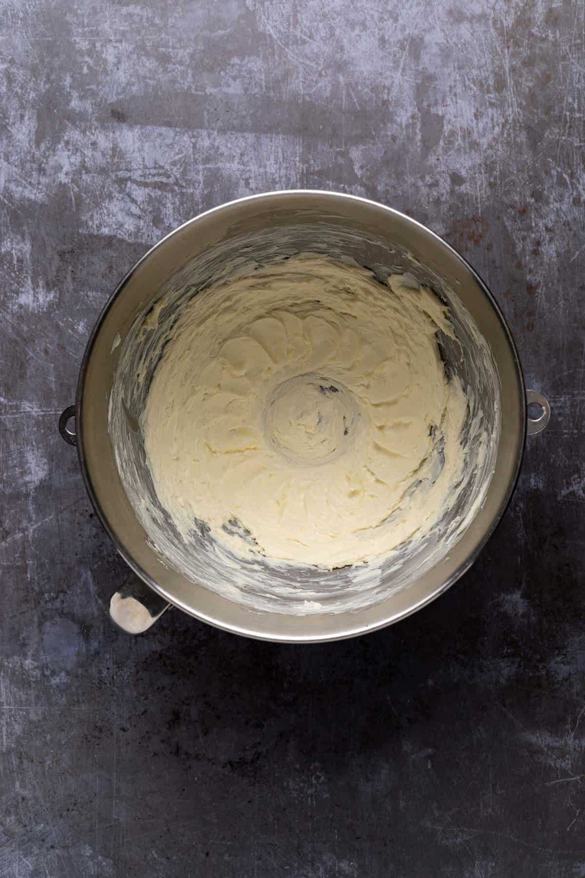 Creamed butter in a stand mixer metal mixing bowl on a flat surface.