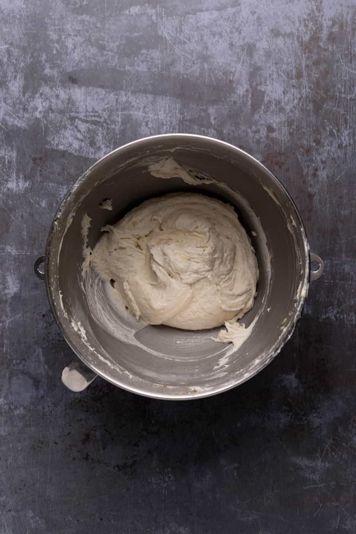 Banana buttercream frosting mixed in a stand mixer mixing bowl set on a flat surface.