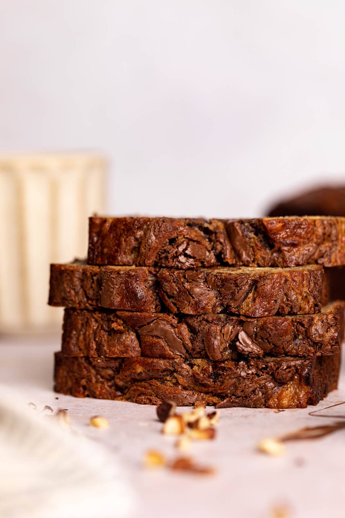 Stack of slices of banana hazelnut bread set on a flat surface.