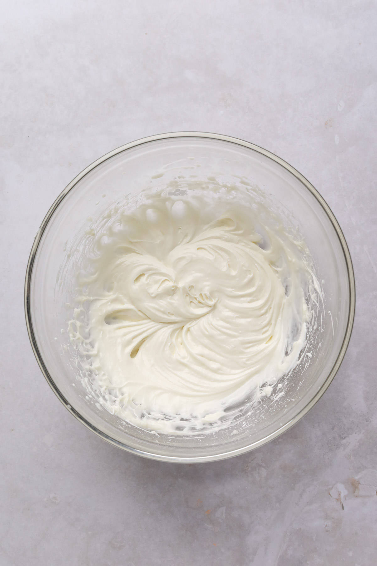 Mixed cream cheese glaze in a glass mixing bowl.