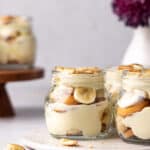 Close up of 3 banana puddings layered in a glass mason jars with sliced banana and vanilla wafers.