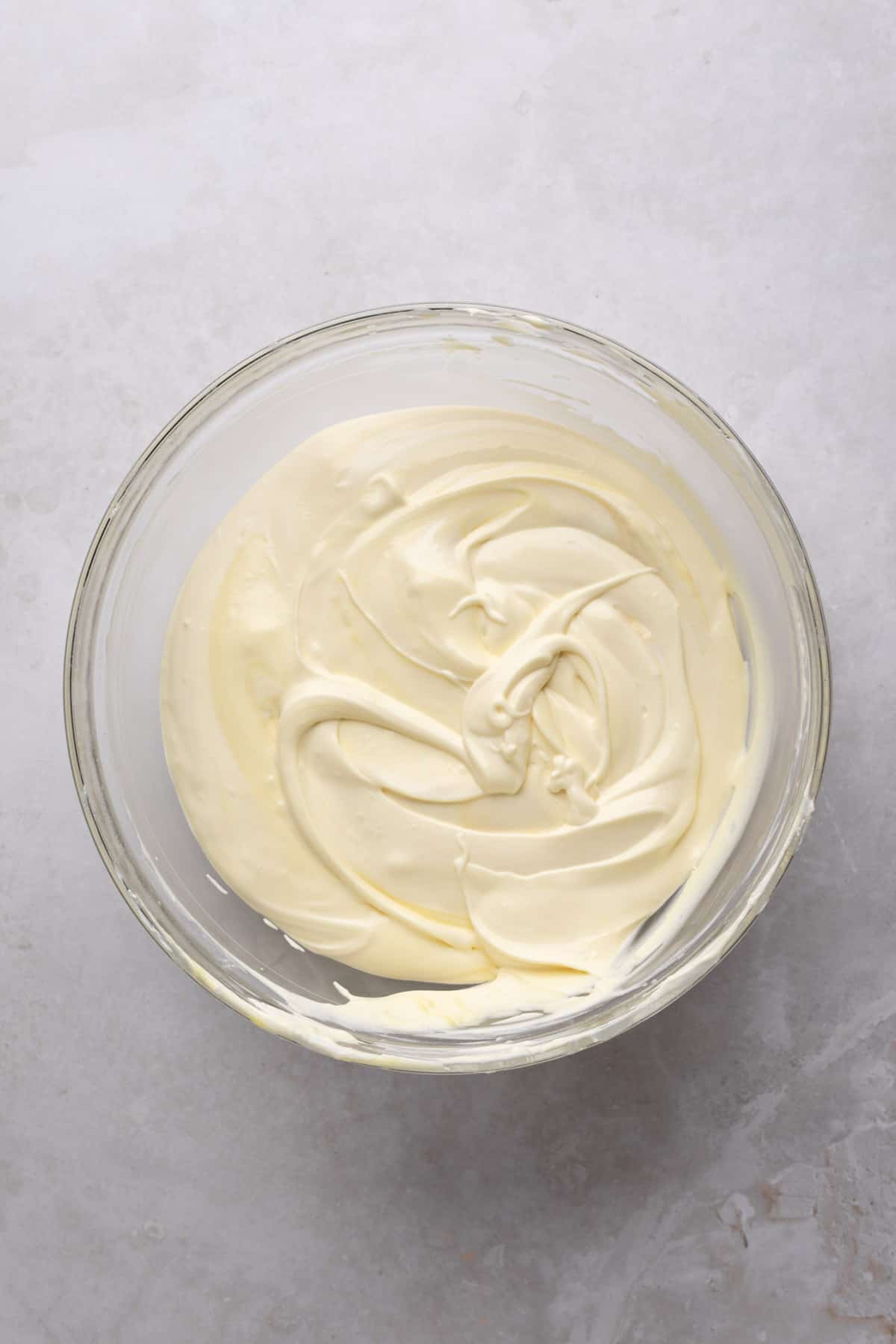 Vanilla pudding mixture combined with whipped cream in a glass mixing bowl on a flat surface.