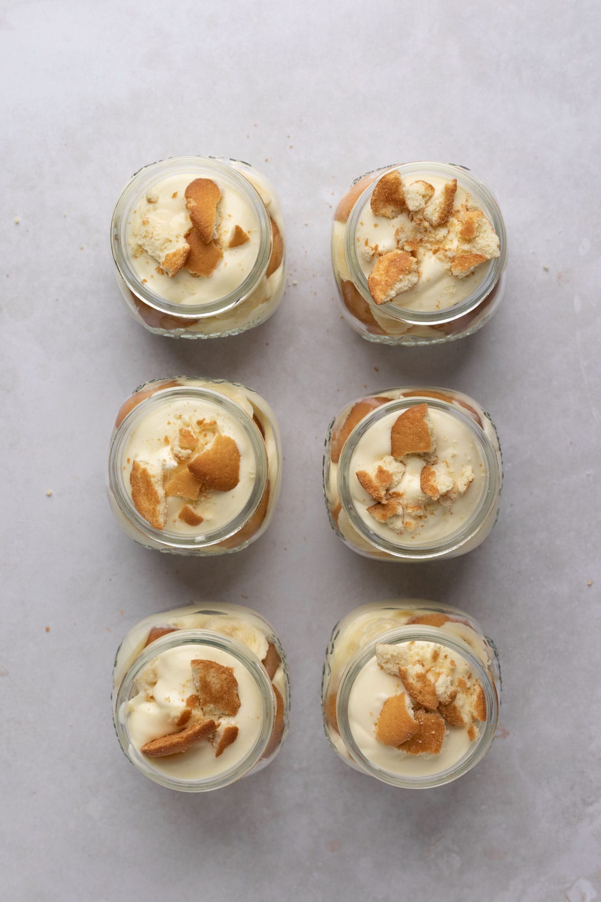 Six mason jars of banana pudding parfaits on a flat surface.