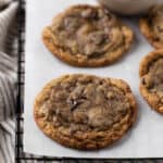 Coffee chocolate chip cookies on parchment paper set on a black wire cooling rack.