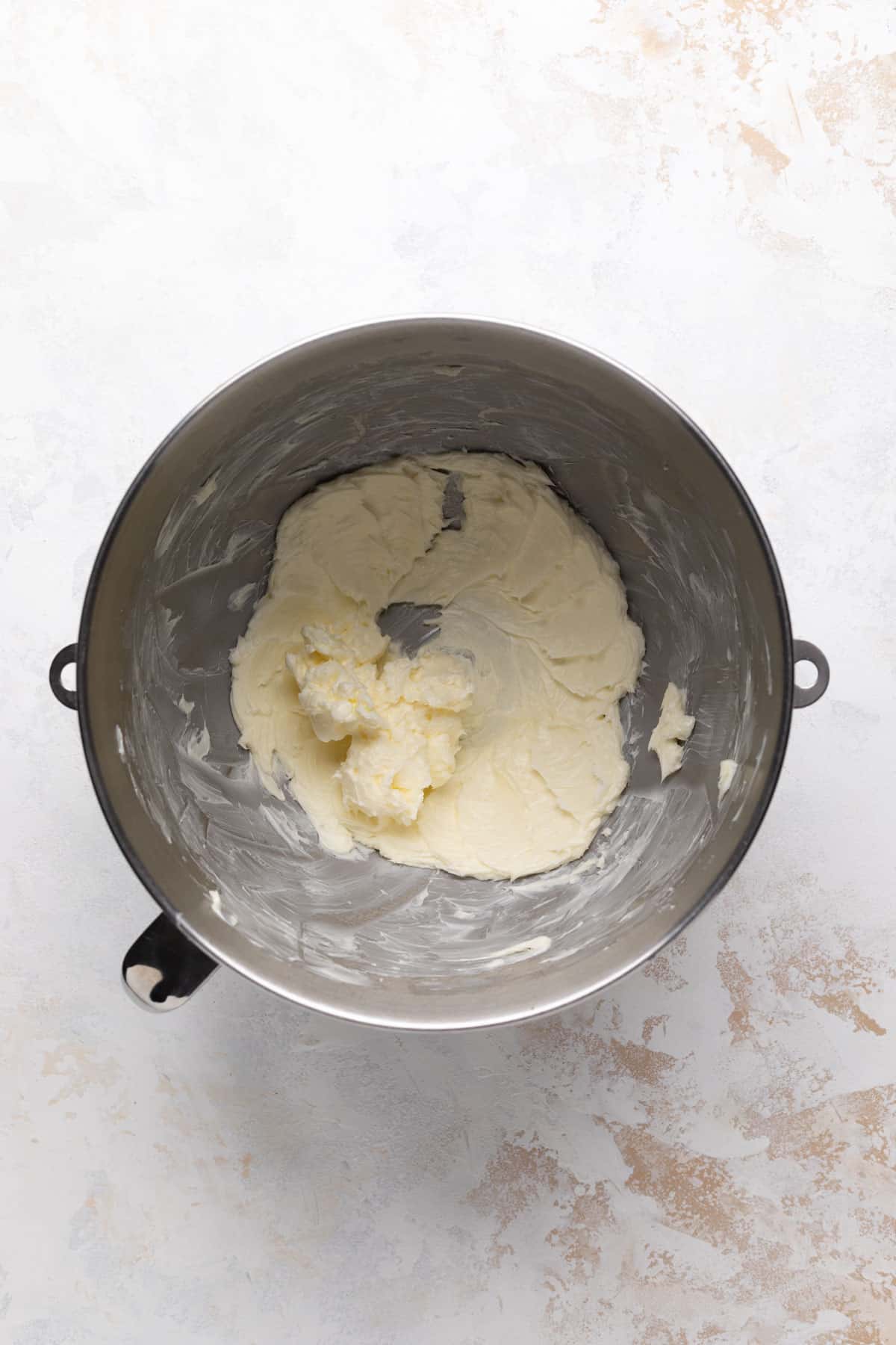 Creamed butter in a metal stand mixer bowl set on a flat surface.