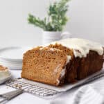 Partially sliced carrot cake pound cake log set on a rectangular wire cooling rack.