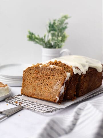 Partially sliced carrot cake pound cake log set on a rectangular wire cooling rack.