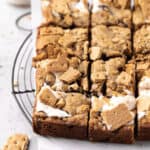 Close up of s'mores blondies on a round wire rack with parchment paper sliced into squares.