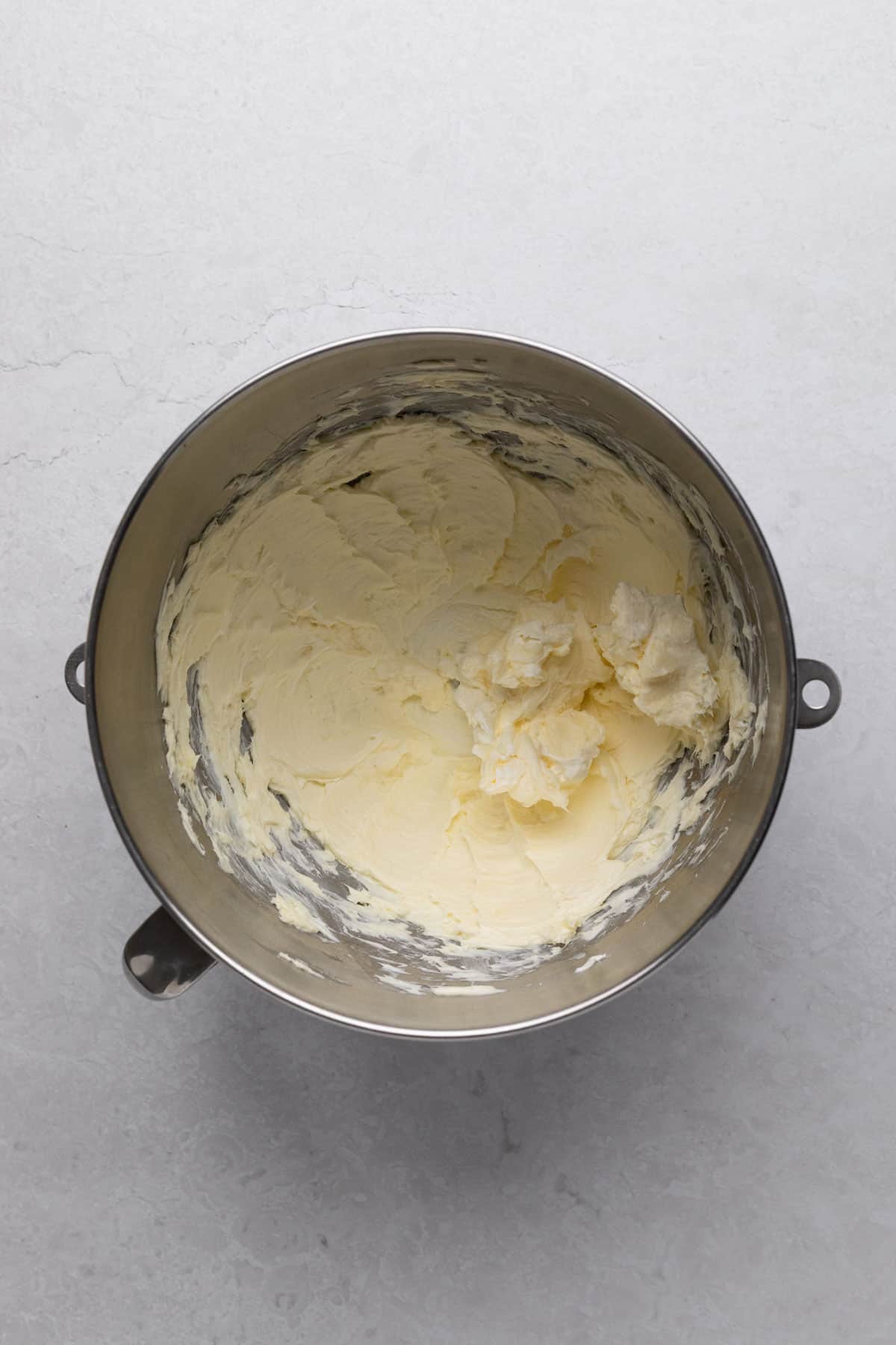 Creamed butter and cream cheese frosting in a metal stand mixer bowl.