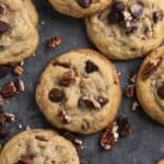 Close up overhead shot of chocolate chip pecan cookies set on a grey flat surface.