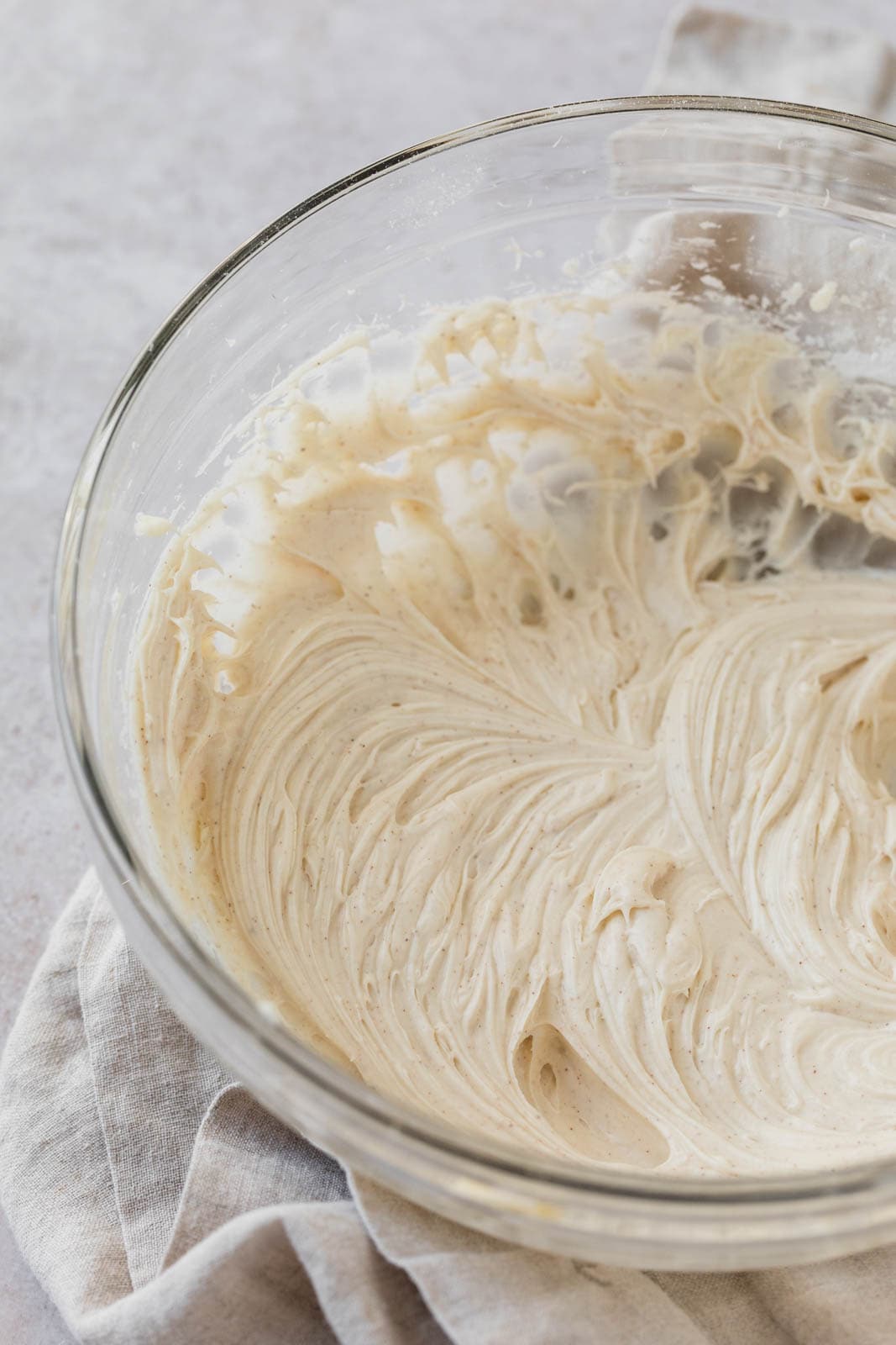 Maple cream cheese frosting in a glass mixing bowl.