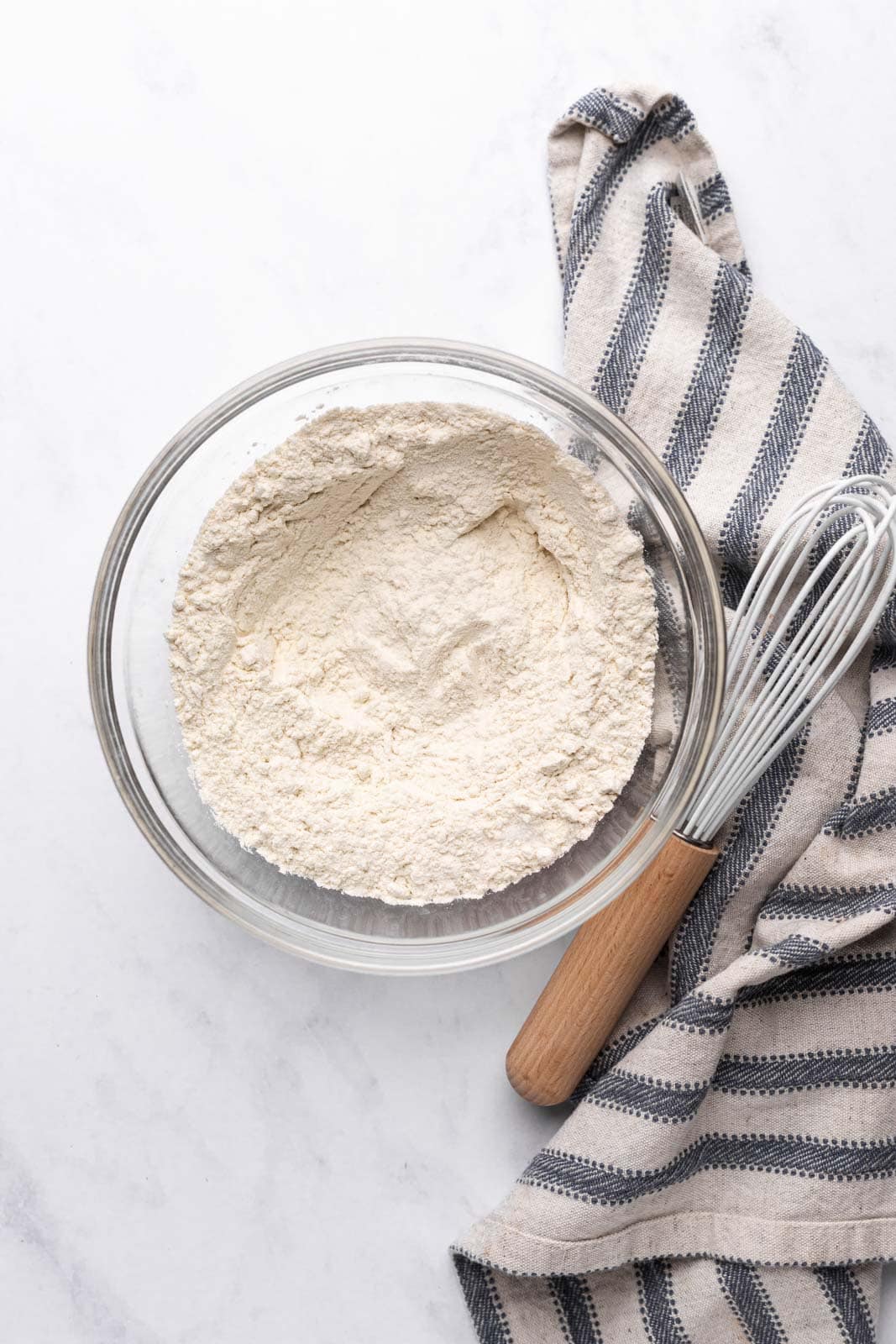 Whisked dry ingredients in a glass mixing bowl set on a flat surface.