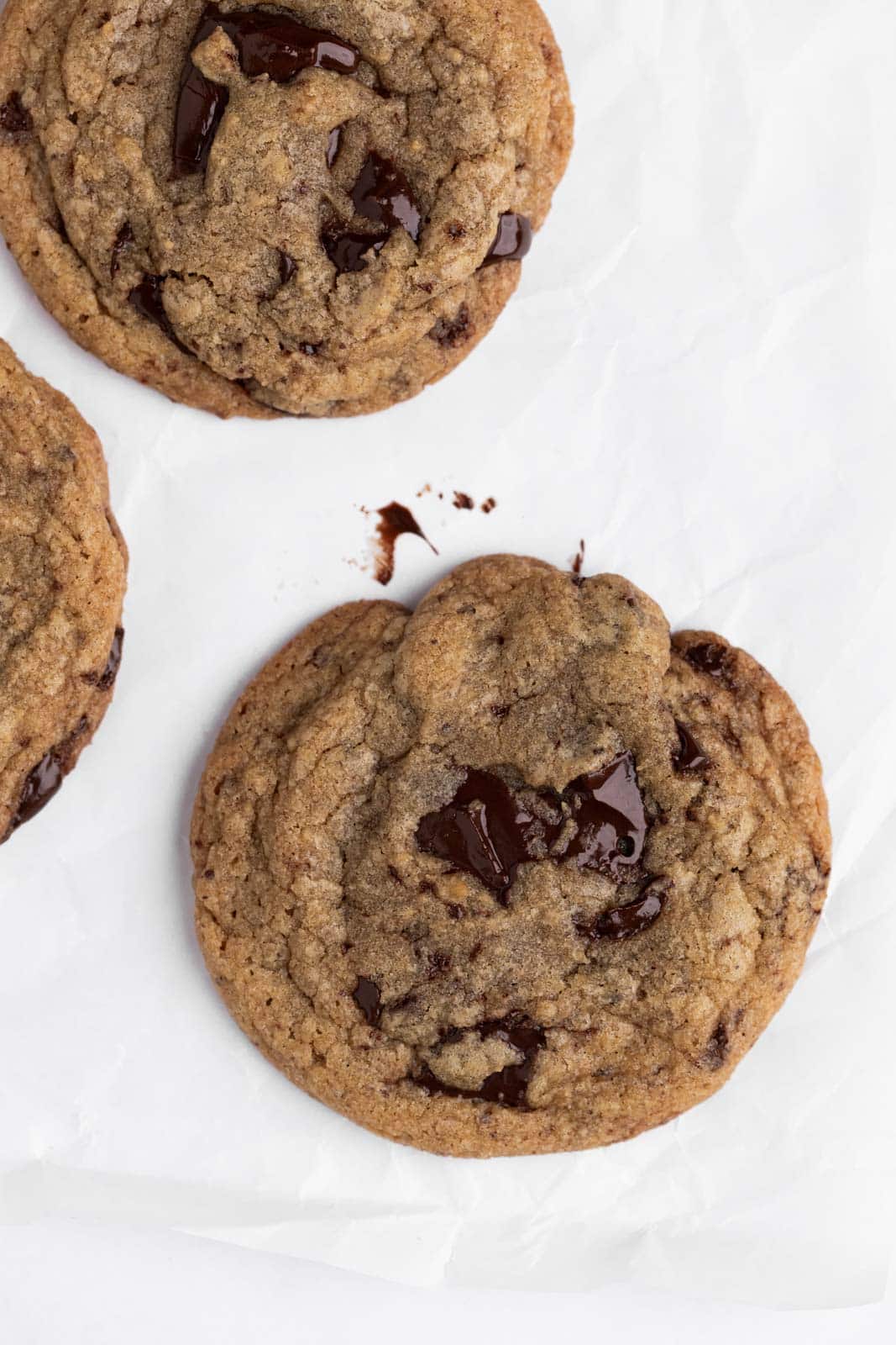 Close up of brown butter chocolate chip cookie set on parchment paper.
