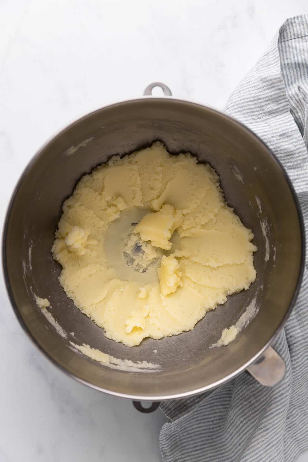 Creamed butter and sugar in a metal mixing bowl set on a flat surface.
