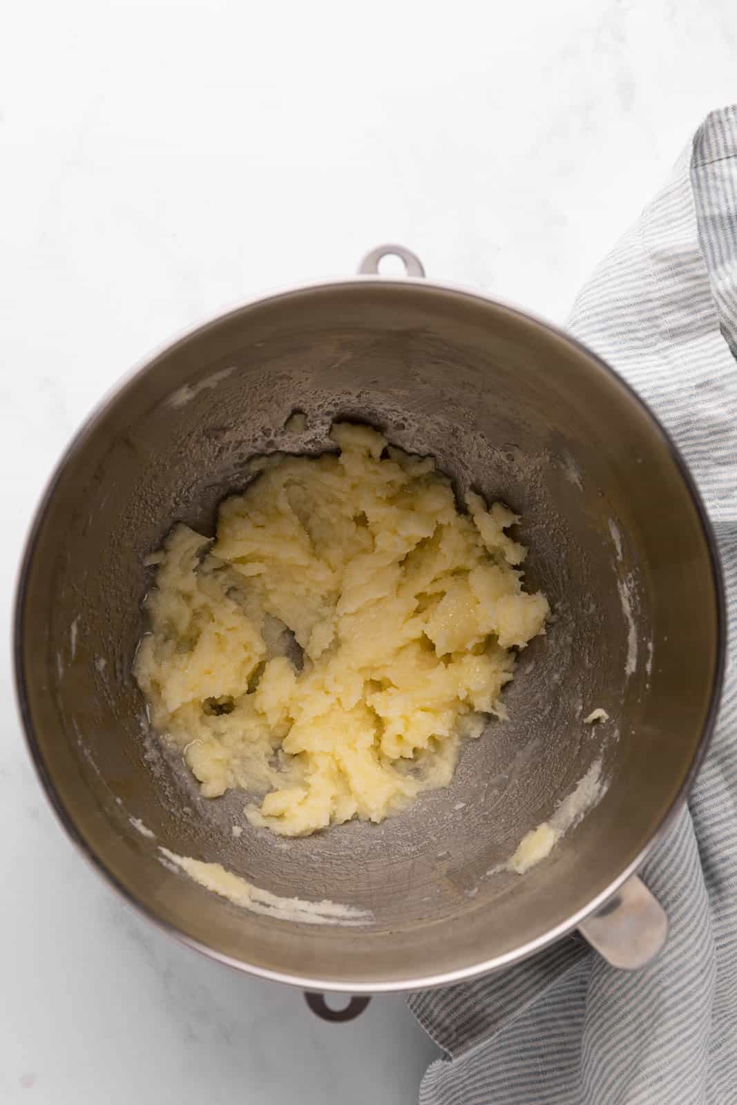 Cream butter and sugar mixed with vegetable oil in a metal mixing bowl set on a flat surface.