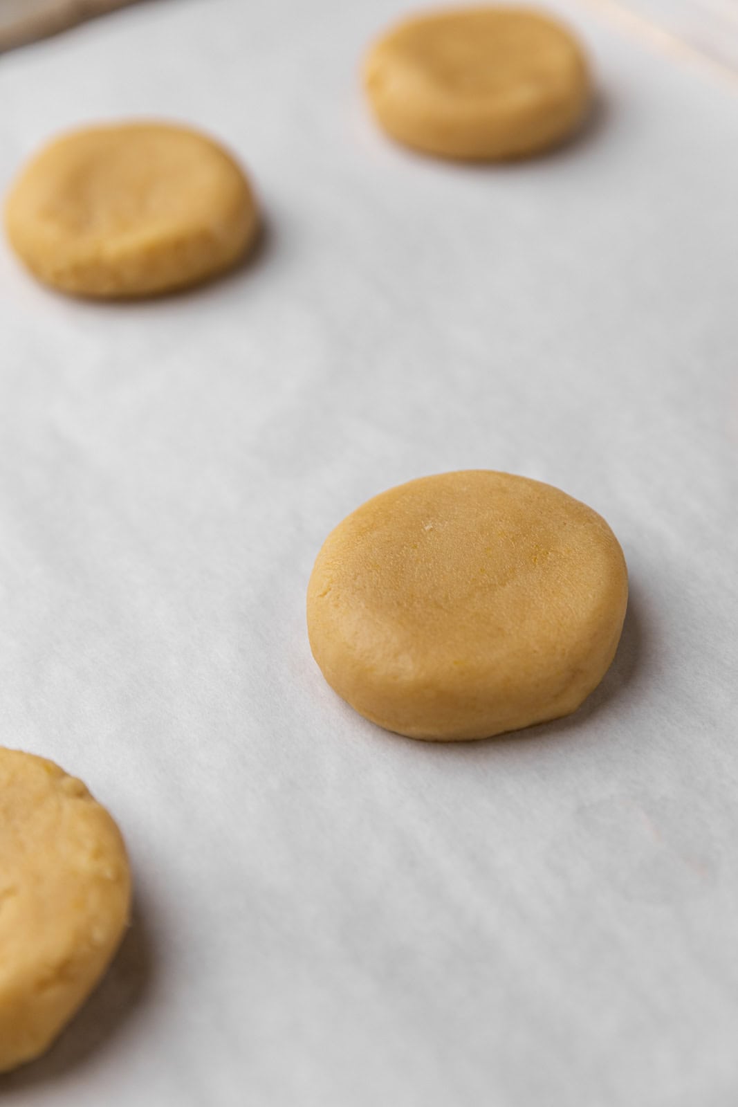 Close up of vanilla sugar cookie dough ball set on a parchment lined sheet pan.
