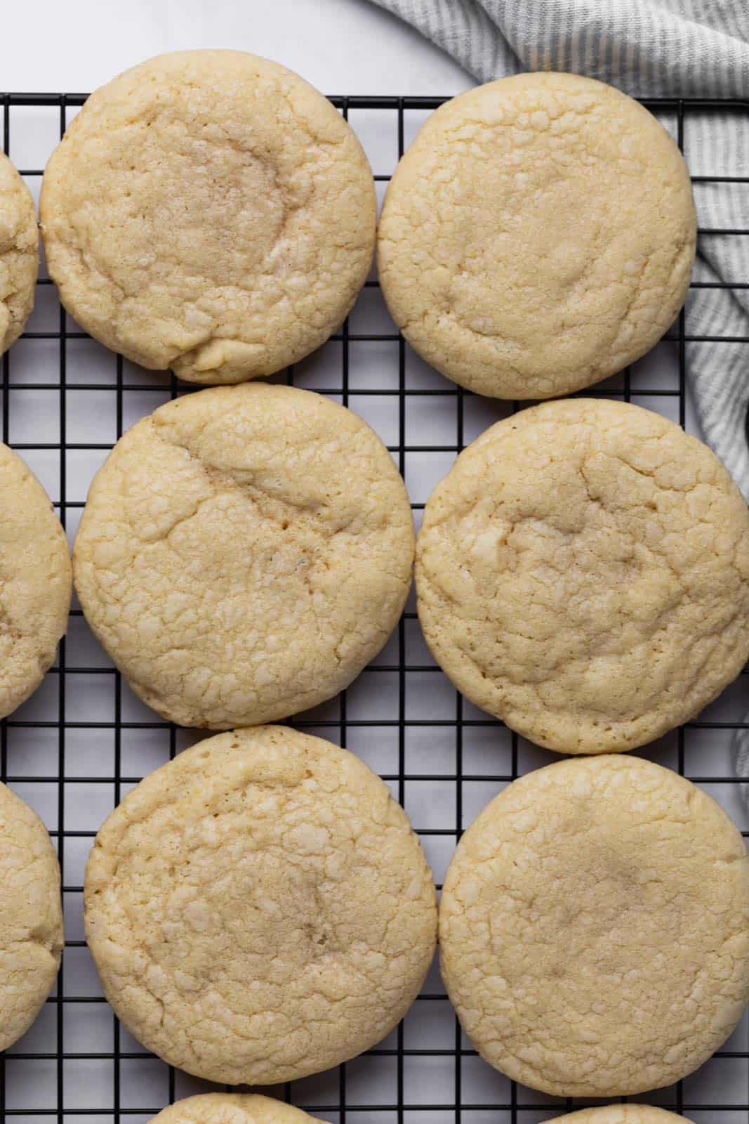 Baked vanilla sugar cookies set on a black wire cooling rack.