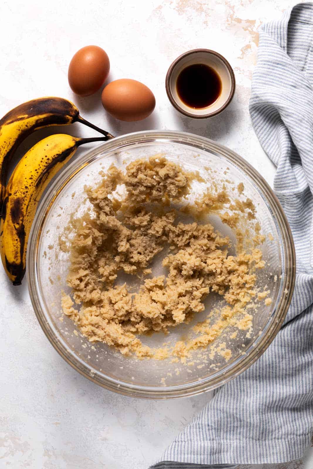 Creamed butter and sugar in a glass mixing bowl set on a flat surface.