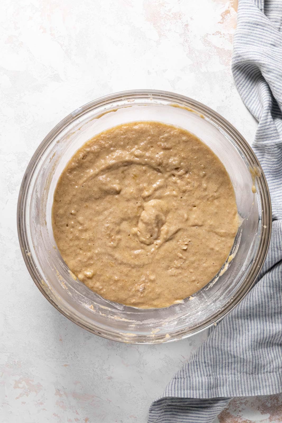 Banana can batter mixed in a glass mixing bowl set on a flat surface.