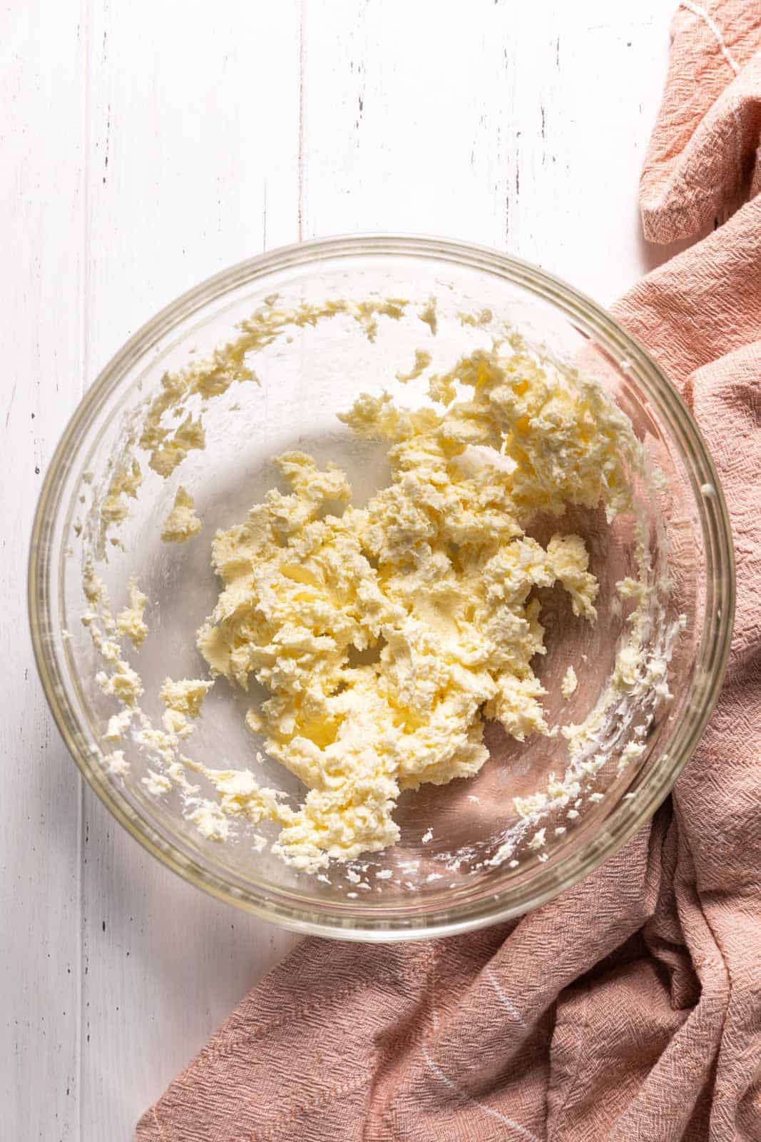Creamed butter and cream cheese in a glass mixing bowl.