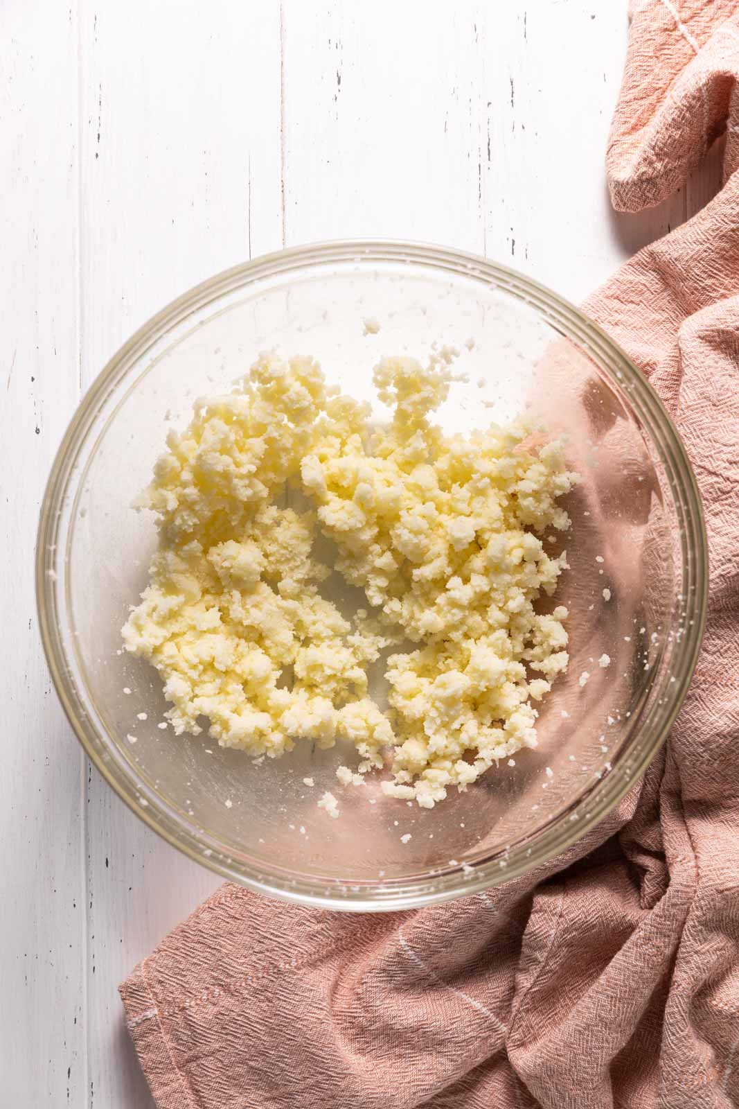 Creamed butter and sugar in a glass mixing bowl set on a flat surface.