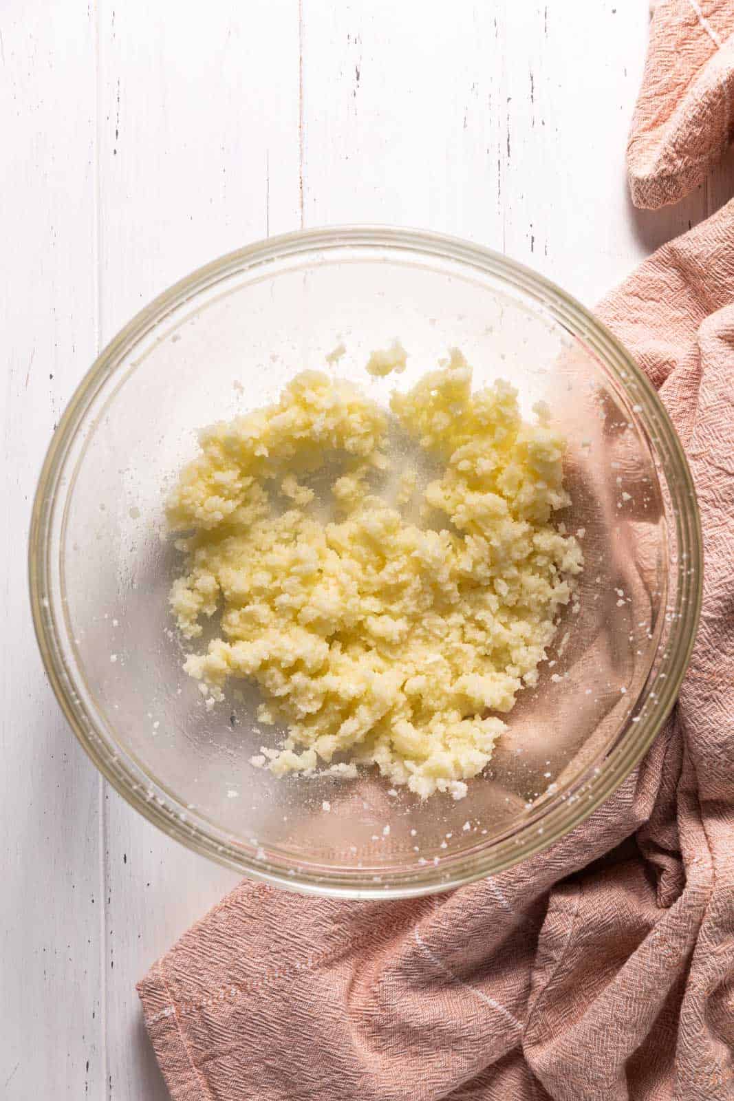 Creamed butter and sugar with oil in a glass mixing bowl set on a flat surface.