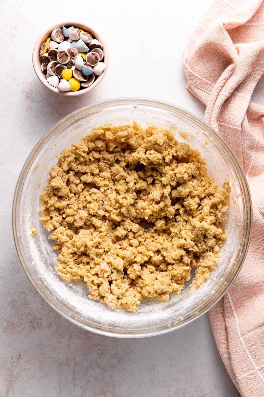 Dry ingredients mixed into creamed butter and sugar with eggs and vanilla for a base cookie dough in a glass mixing bowl set on a flat surface.