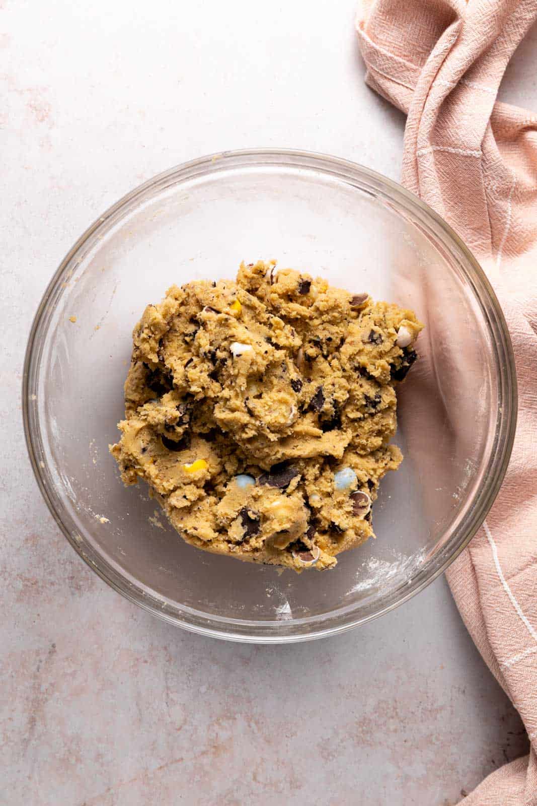 Mini egg cookie dough mixed in a glass mixing bowl set on a flat surface.