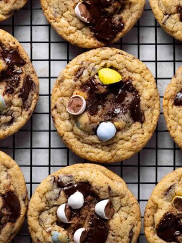 Overhead shot of baked mini egg cookies set on a black wire rack.