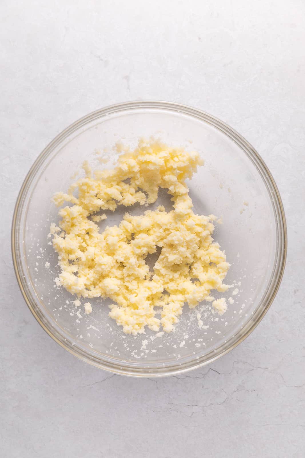 Creamed butter and sugar in a glass mixing bowl on a flat surface.