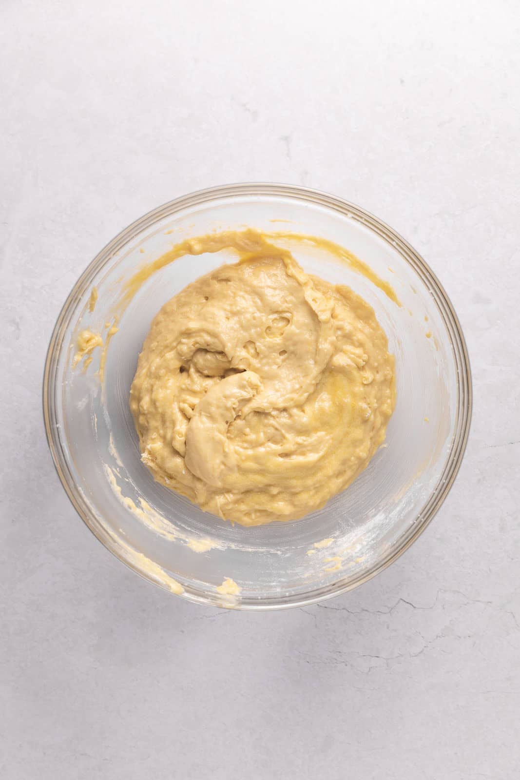 Vanilla cupcakes batter in a glass mixing bowl set on a flat surface.