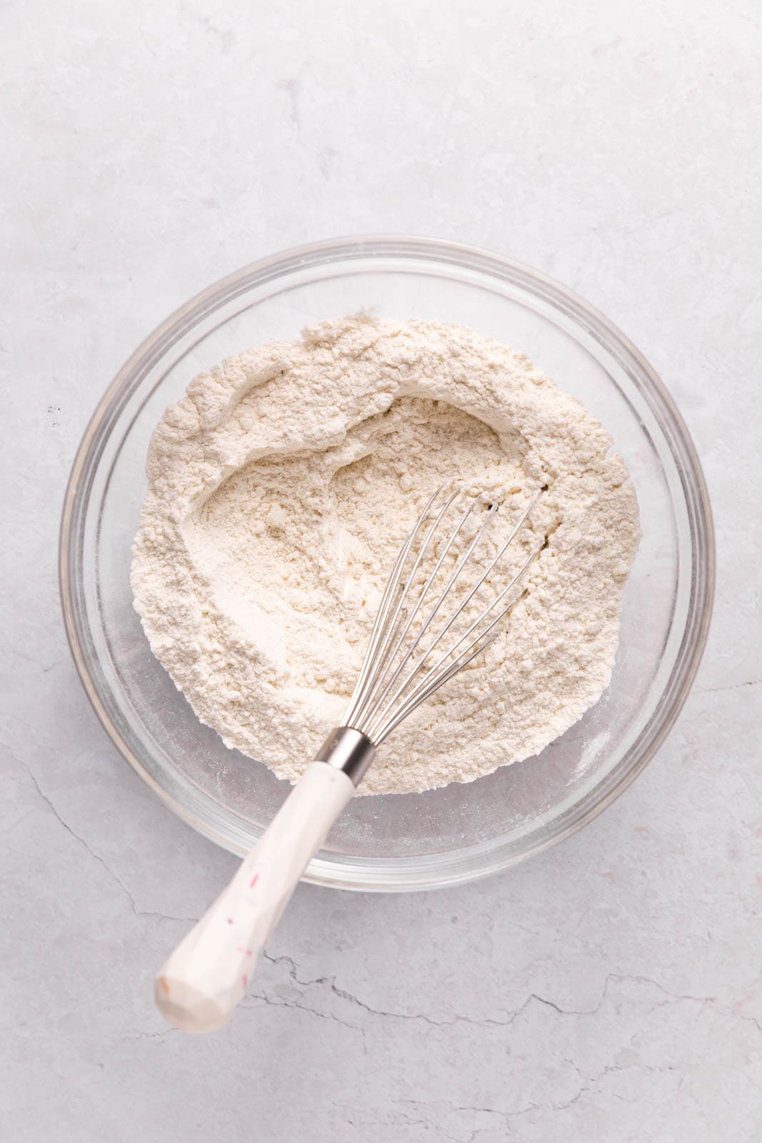 Whisked dry ingredients in a glass mixing bowl on a flat surface.