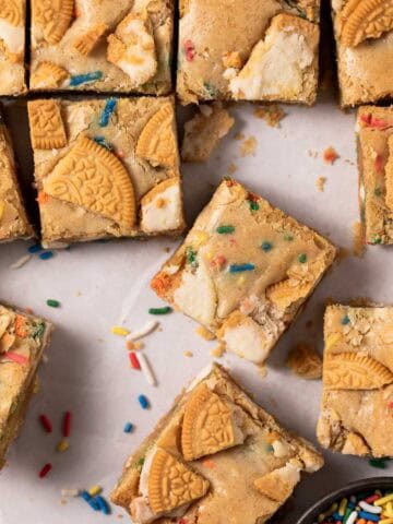 Overhead shot of birthday cake blondes cut into squares with sprinkles around.