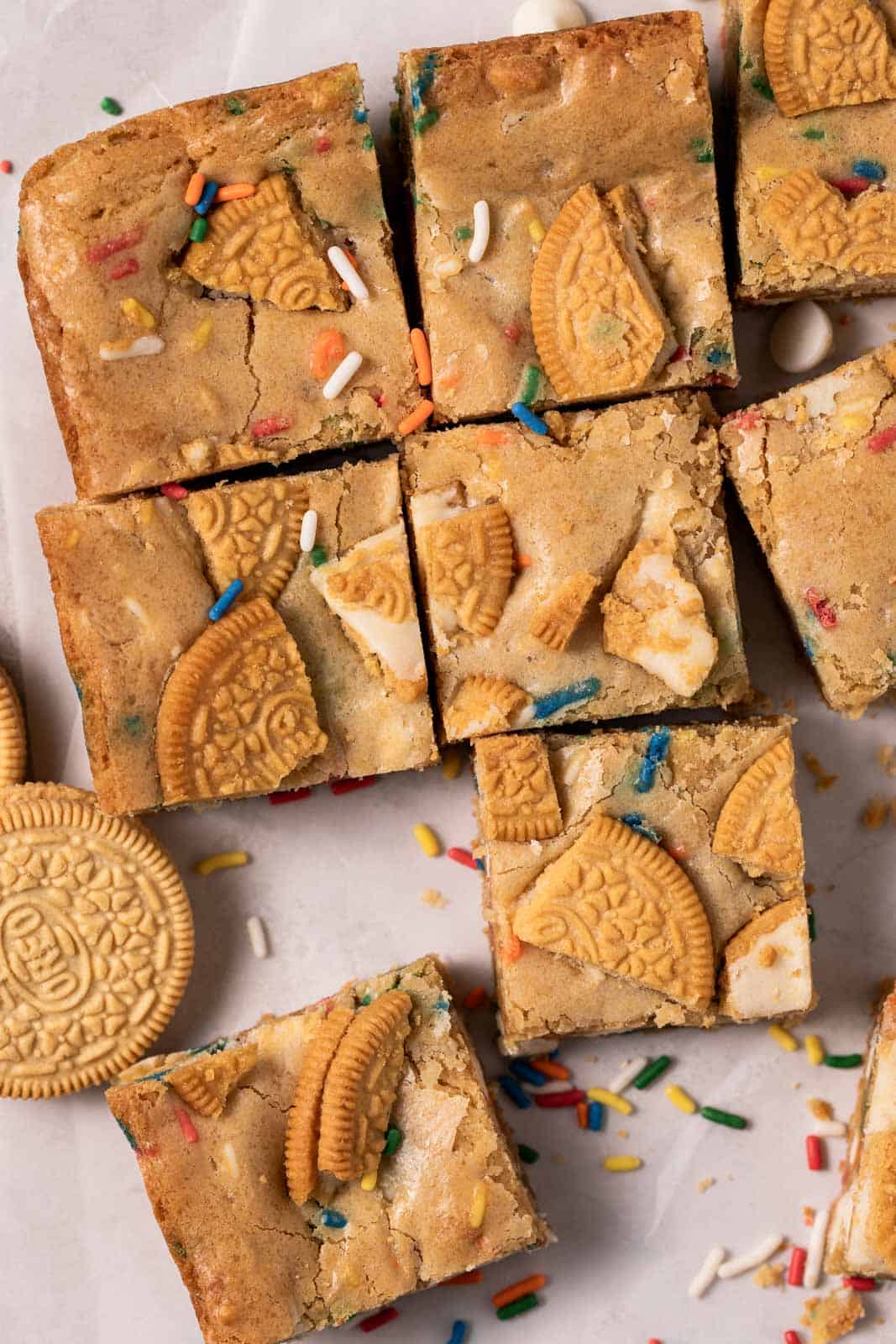 Overhead shot of birthday cake blondes cut into squares with sprinkles and Golden Oreos around.