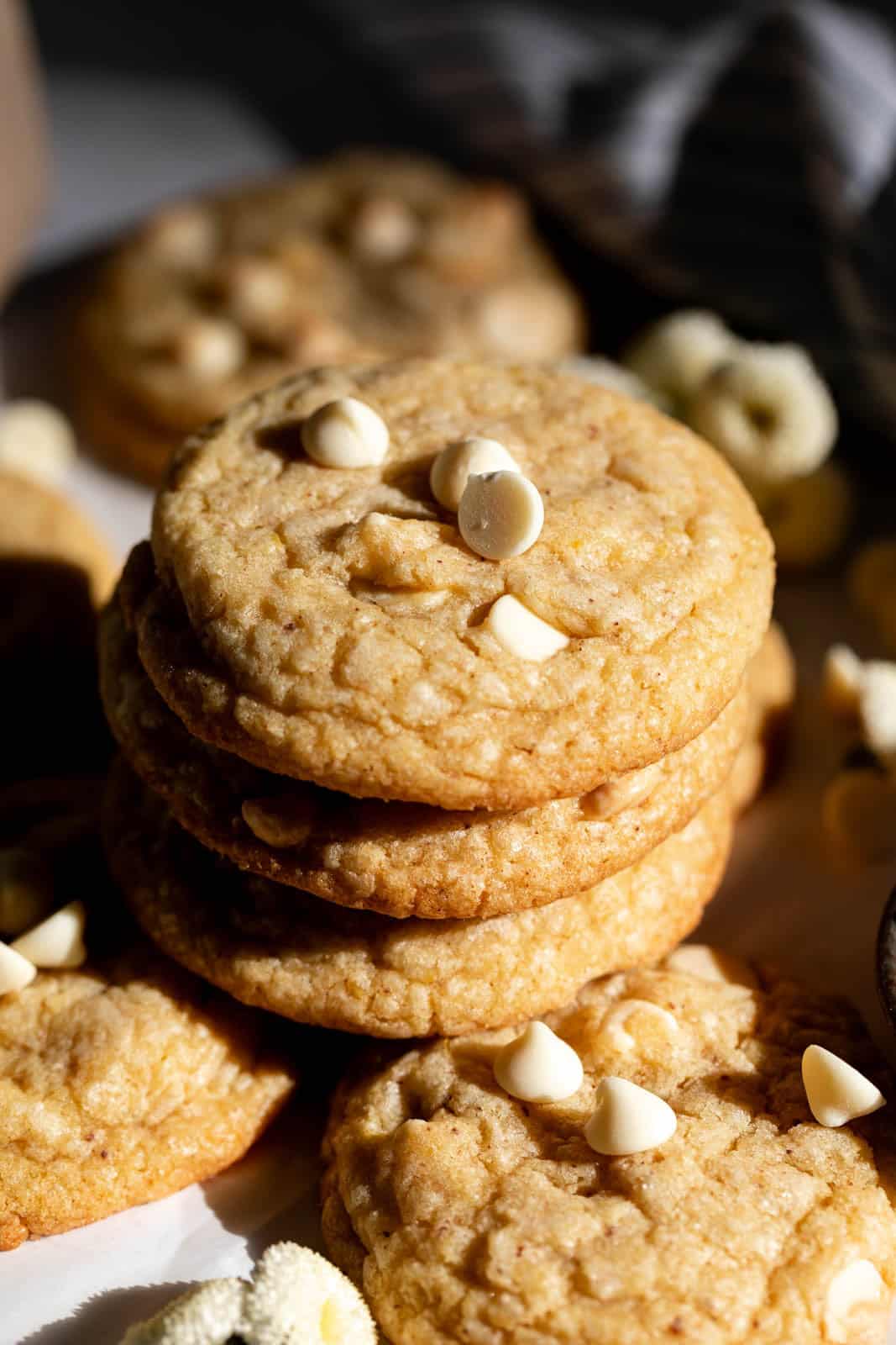 Close up of a stack of lemon white chocolate chip cookies set on white parchment paper.