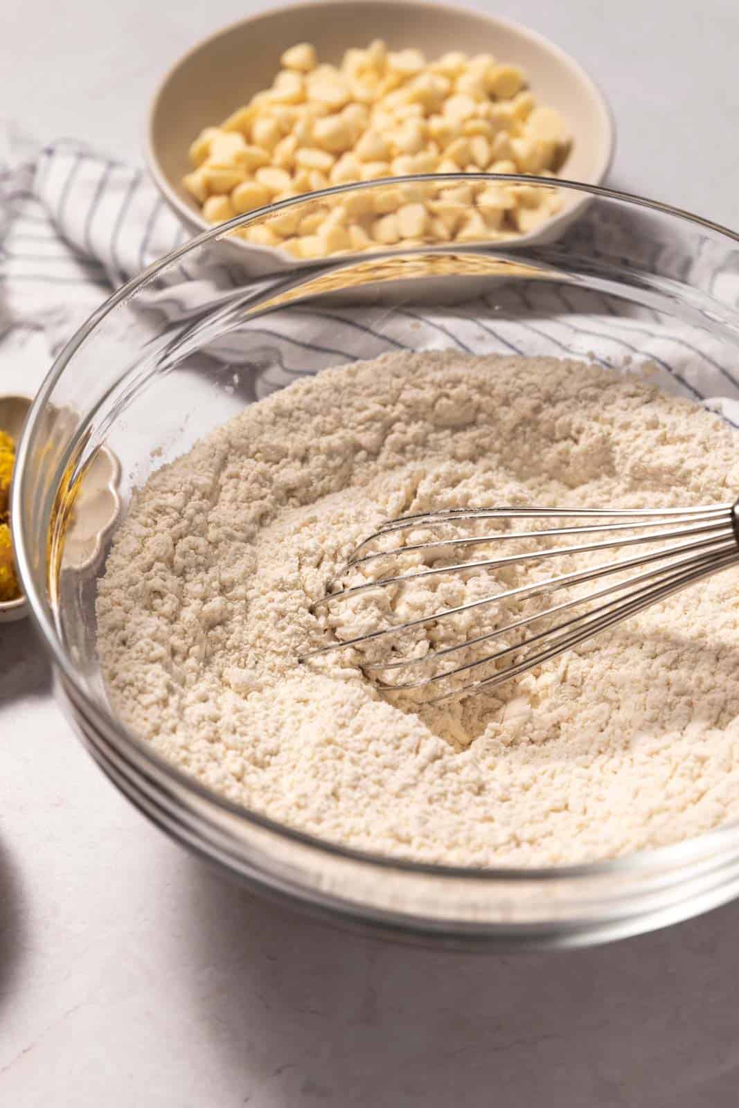 Whisked dry ingredients in a glass mixing bowl with a wire whisk.